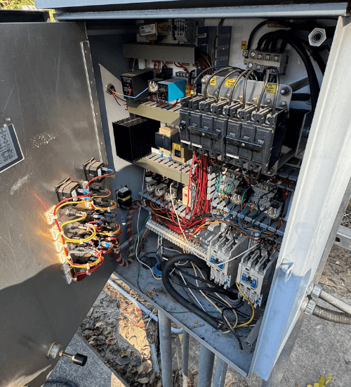 Open electrical control panel showing wiring, circuit breakers, and relays for an industrial pump system during inspection or maintenance.