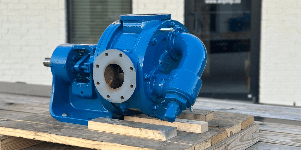 Rebuilt industrial pump freshly painted blue and staged on a wooden pallet outside the EV Pump & Equipment facility.