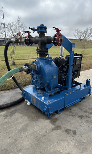 Rebuilt Tier 3 trash pump skid painted blue on a steel frame with forklift pockets. Features discharge piping with butterfly and ball valves, green suction hose, and a diesel engine with control panel. Photographed on concrete in Lafayette, LA.