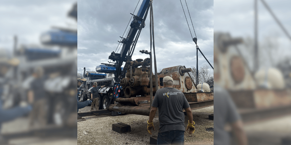 Large mud pump being crane-lifted off a flatbed at EV Pump & Equipment's yard — Lafayette, LA