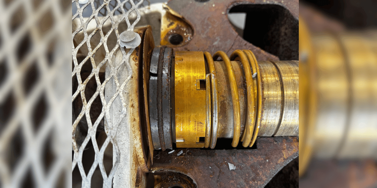Failed mechanical seal on a centrifugal pump shaft at EV Pump’s shop in Scott, Louisiana, showing the worn brass seal assembly, spring, and rust on the bearing frame
