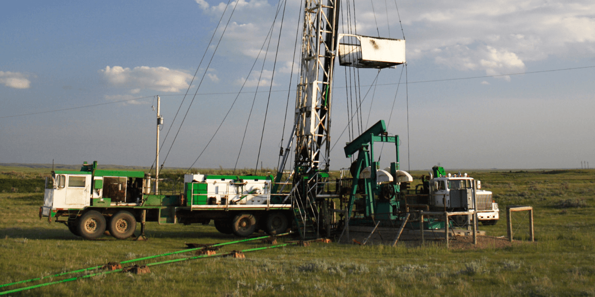 trucks, machinery, and pumps on site in a field to complete water well servicing